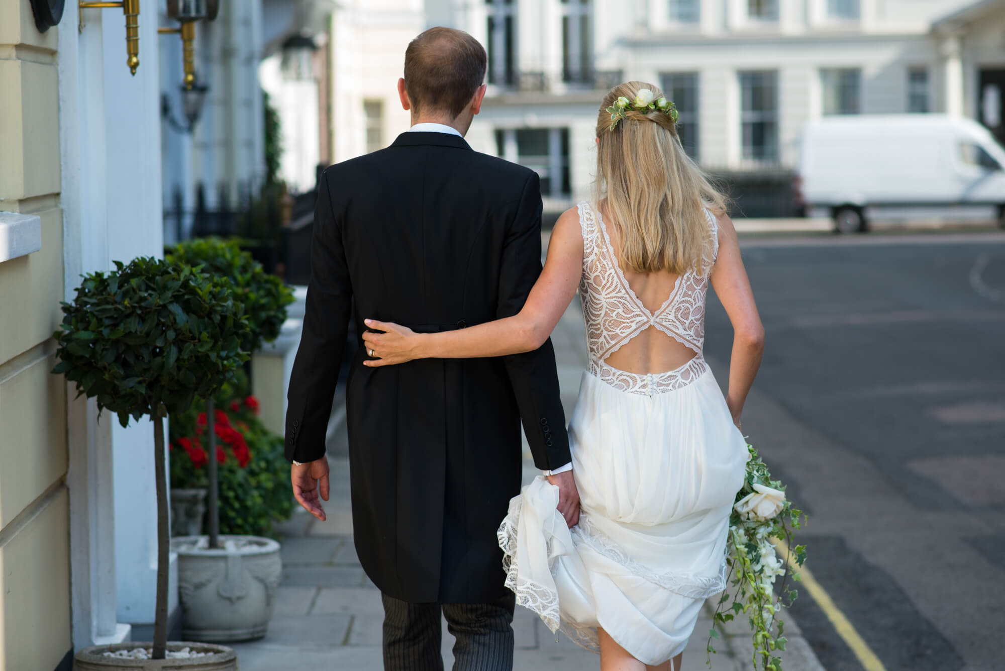 A bride and groom walking on the pavement in London